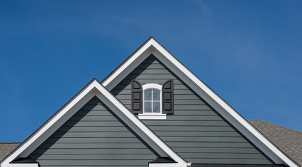 Attic window with black shutter on grey blue siding, gable, corbel, louver on a new construction...