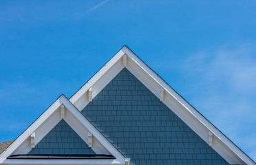 Plastic or wood white roof decoration gable, corbel, louver on a new construction luxury American single family home in the East Coast USA with blue sky background