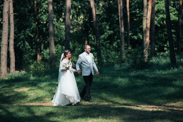 Bride and groom are walking in the woods on their wedding day