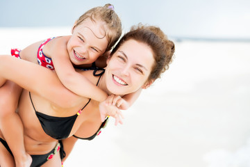 Fototapeta premium Portrait of happy mother and little daughter on sunny beach on Maldives at summer vacation