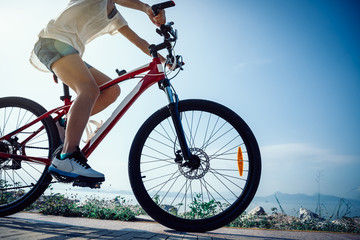Fototapeta na wymiar Woman cyclist riding Mountain Bike on sunrise seaside