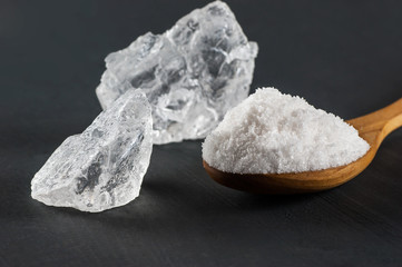 Pure natural white crystal bath or rock salt with food or sea salt in wooden spoon on wooden background