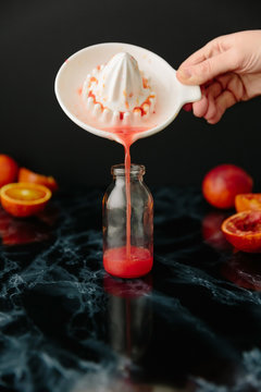 Woman pouring blood orange juicer into bottle