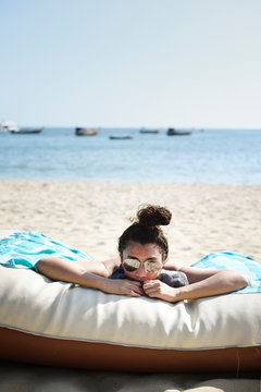 Young woman on a blow up beach chair in the sand