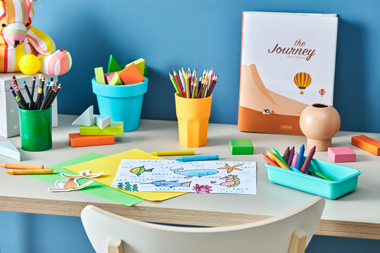 Kid's Painting On The Desk With Crayons.