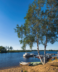 Naklejka na ściany i meble Panoramic summer view of Iijoki river near Municipality of Ii in the region of Northern Ostrobothnia, Finland. The old wooden pier and boat on the shore