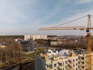Fototapeta na wymiar Aerial of a building site with a large operating bright yellow crane near a house