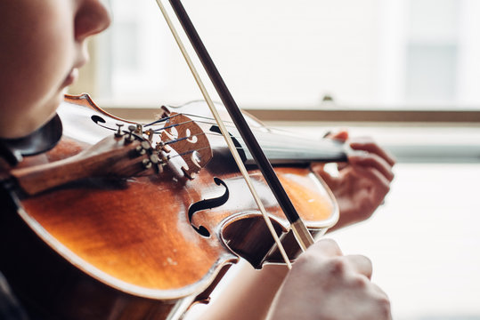 Young girl practicing violin by a window