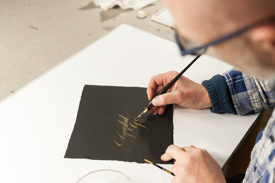A Master Calligrapher writing elegant cursive lettering with a nib mounted on a oblique holder