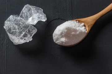 Pure natural white crystal bath or rock salt with food or sea salt in wooden spoon on wooden background