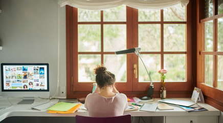 Upset woman sitting at desk against window.