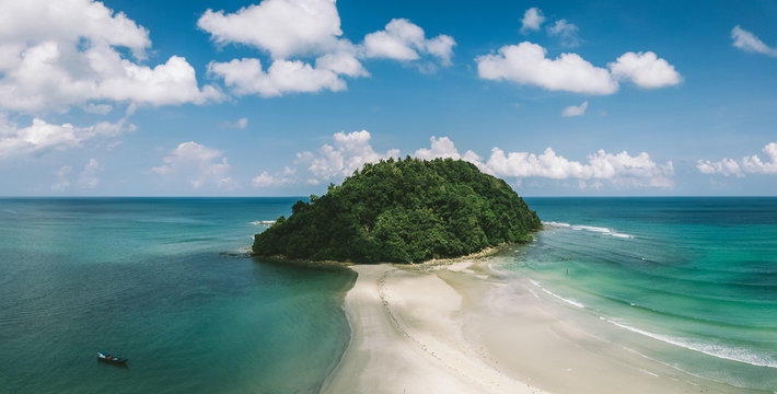 drone shot of green island in emerald waters