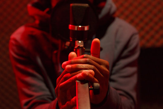 Black man recording track in sound studio on red backgraund