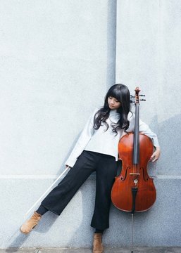 Portraits Of Female Jazz Cellist Standing And Playing In Outdoor Space