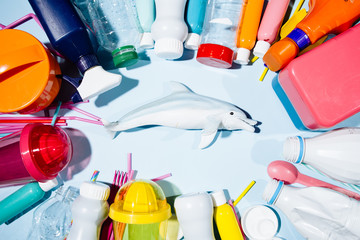Dolphin is circled by different container of plastic over an aqua bacground simulating the sea, conceptual image to represent the plastic sea pollution a major environment worldwide problem.