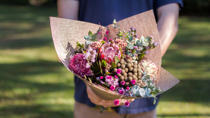 man holding bouquet of Australian native flowers close up in the green garden yard 