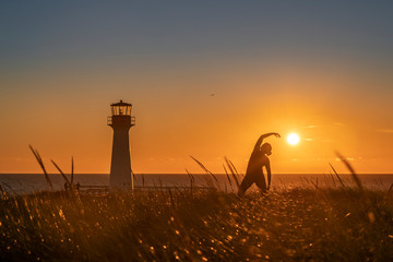 Position du guerrier inversé au couché du soleil aux iles de la Madeleine, Québec, Canada