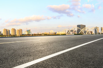 Asphalt road and city skyline with bridge construction in shanghai at sunset