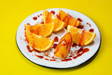 Orange slices with chilli powder and chamoy on colorful background