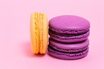 Three colored macaroons on a pink background.