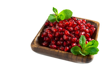 Pomegranate seeds in wooden bowl isolated on white background.