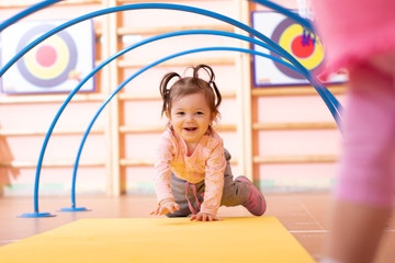 Baby girl crawling on mat in gym class. Lifestyle concept of children activity.