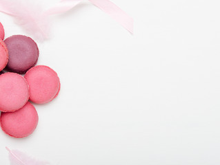 Multicolored pink macaroons on a white background with ribbons. Sweet treat, pastries, high-calorie food. Copy space, top view, flat lay