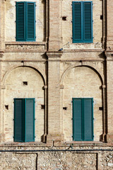 Four shuttered windows in a geometric brick wall in European style