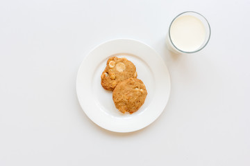 High angle view of homemade cookies on plate with glass of milk on white background