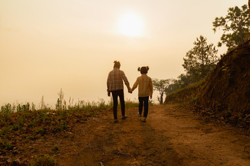 Two children walking on mountain trail at sunset