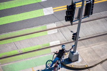 Woman on bicycle is preparing to cross the road at pedestrian crossing