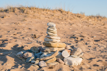 Fototapeta na wymiar Sea stones folded into the tower. Child Game. Fun on the beach. Stable construction.