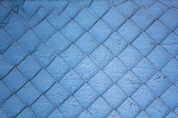 damaged metal net on a blue white gray shabby dirty wall  cracked. rough surface texture