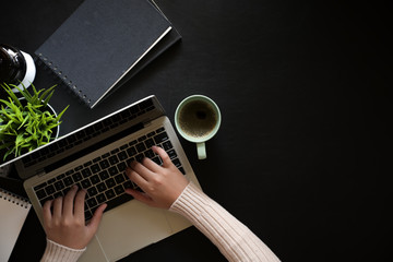 Top view woman using laptop on dark leather workspace desk