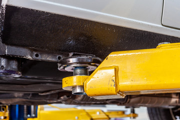 Car lift arm holding a vehicle in a workshop extreme closeup