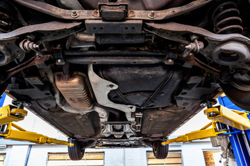 Fototapeta View of car undercarriage when lifted on hydraulic lift in a workshop during inspection obraz