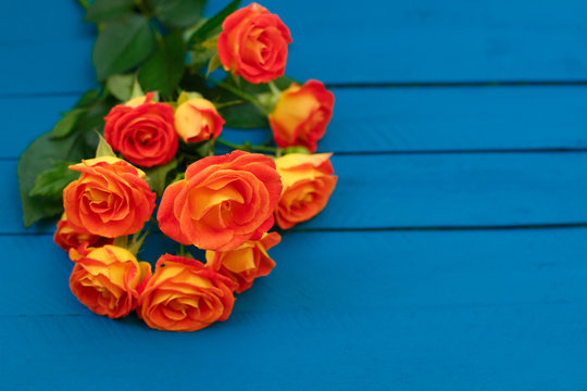 Background of a bouquet of beautiful fresh vivid orange roses tinged with red for celebrating an anniversary, birthday or Mothers Day