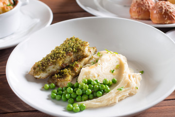 Fried fish with herbs and spices with mashed potatoes and green peas