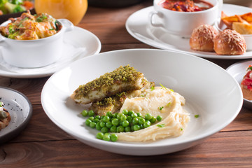 Fried fish with herbs and spices with mashed potatoes and green peas