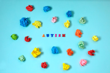 Autism spectrum disorder from color letters surrounded by scattered colorful crumpled paper on blue background. April Autism awareness month