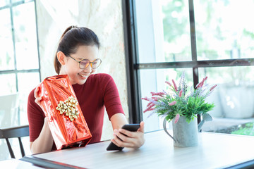 Young woman holding gift box and video call 