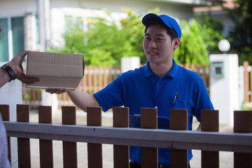 happy Asia young delivery man in blue cap standing with parcel post box 