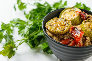 Boiled quinoa, baked vegetables and herbs in a bowl on the table. Vegetarian dish.