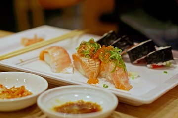 Salmon sushi on top with rice, side dish is a rice with seaweed wrap, main dish for lunch or your dinner, delicious food from good ingredient, relaxing after work.