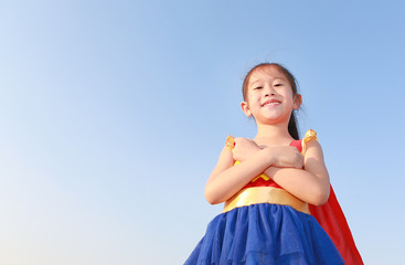 Little child girl Superhero on clear blue sky background. Kid super hero concept.