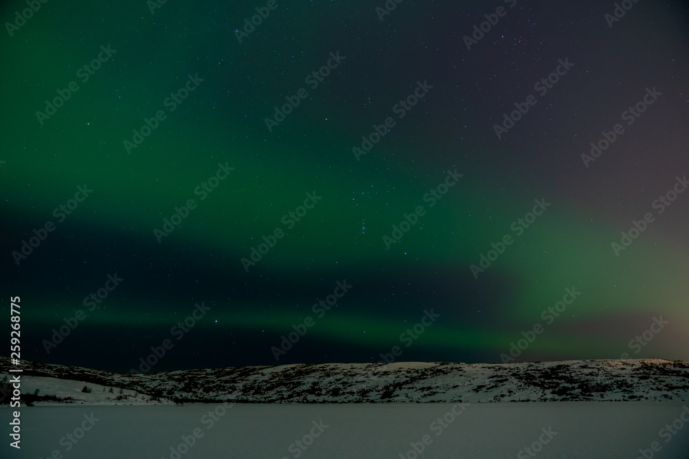 Wall mural northern lights and stars over snowy mountains and frozen lake