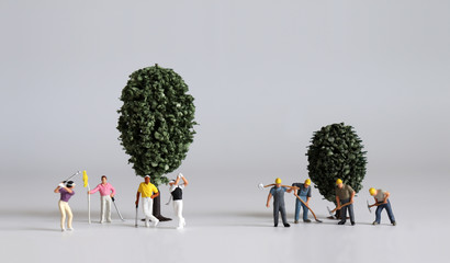 Concept of the gap between rich and poor. Miniature people and miniature trees.