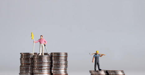Concept of economic inequality. Coins and miniature people. 