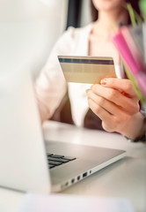Young woman holding credit card and using laptop computer. Online shopping concept.