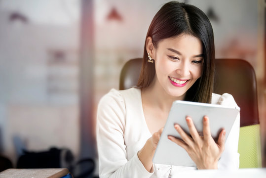 Beautiful woman using tablet while sitting at office desk.